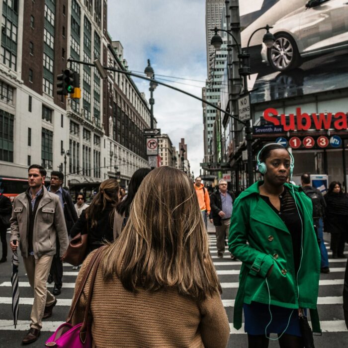 woman wearing green jacket walking on the pedestrian lane during daytime